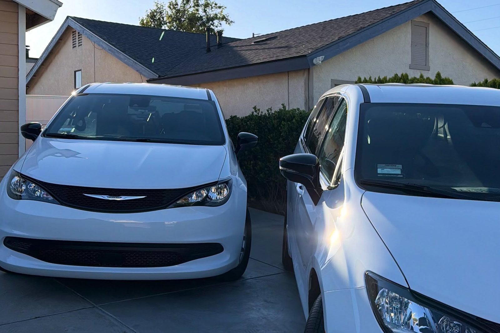 Two white Chrysler Pacificas detailed side by side on a driveway