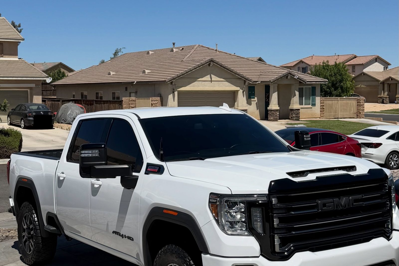 A white GMC Sierra AT4 HD detailed on a residential driveway