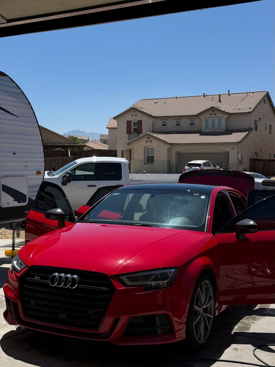 Red Audi S3 parked under a carport, front three-quarter view