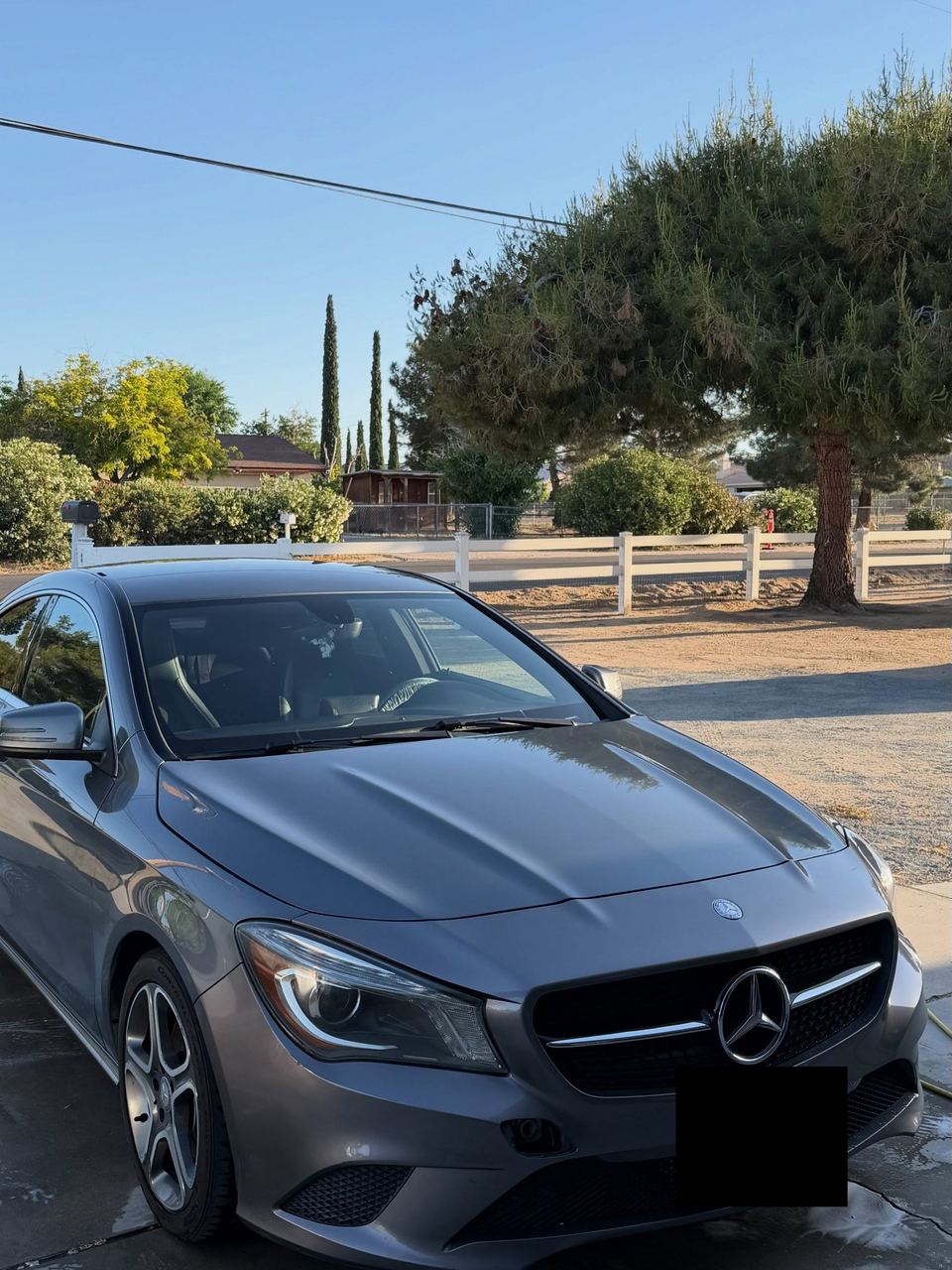 Gray Mercedes-Benz CLA parked in a driveway, front three-quarter view