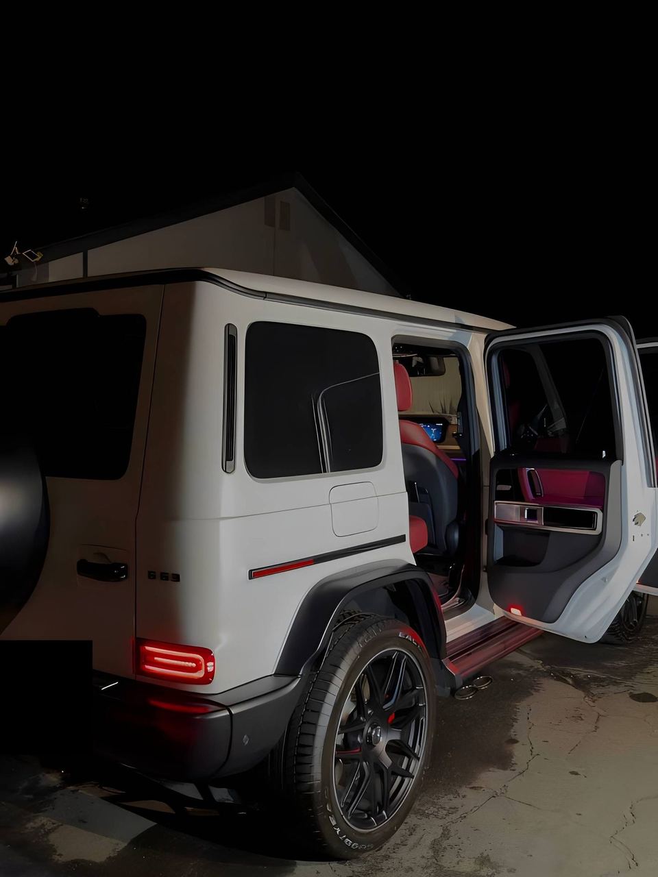 White Mercedes-AMG G63 at night, rear three-quarter view with the door open