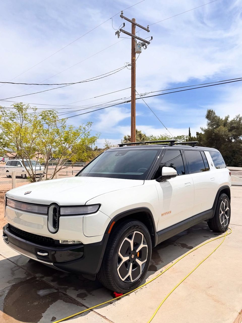 White Rivian R1S parked in a driveway after a wash, front three-quarter view