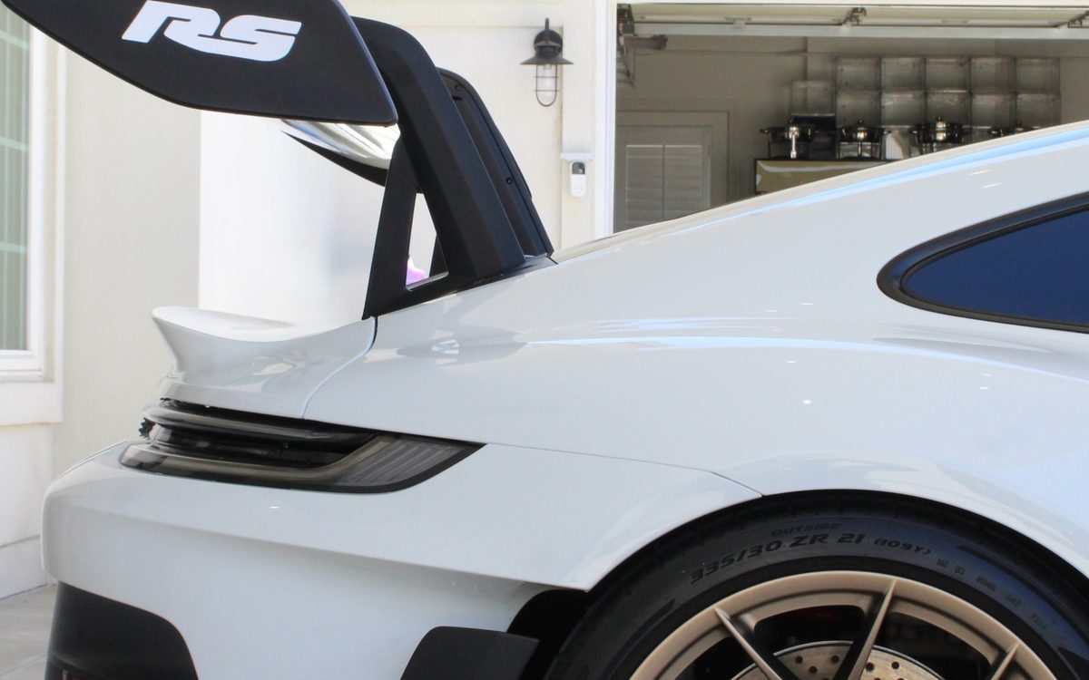 The rear wing and gold wheel of a white Porsche 911 GT3 RS