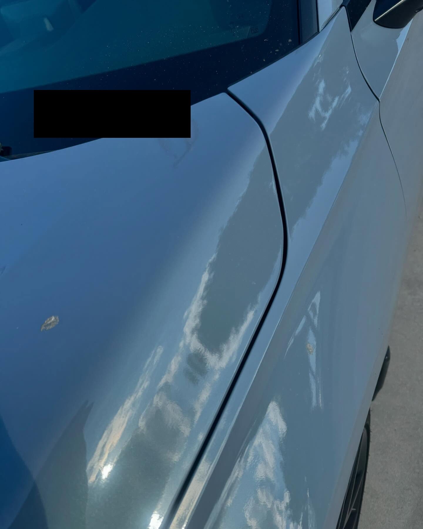 Machine polishing in progress on a dark car panel