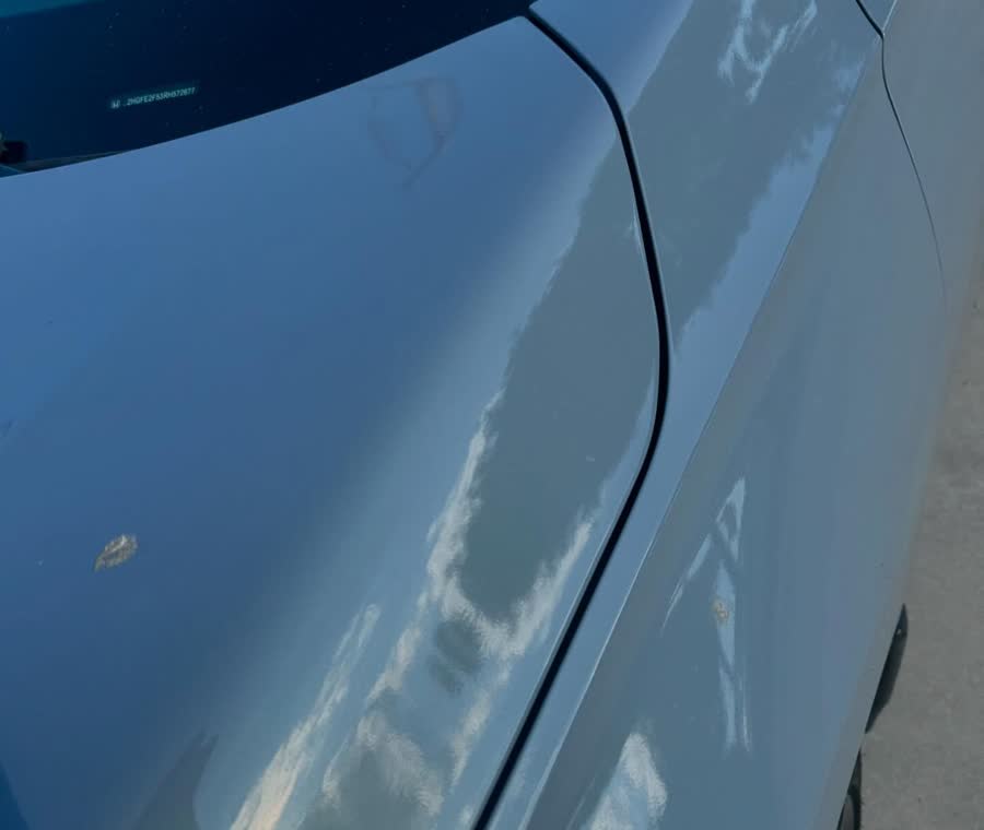 A gray quarter panel reflecting clouds cleanly after machine polishing