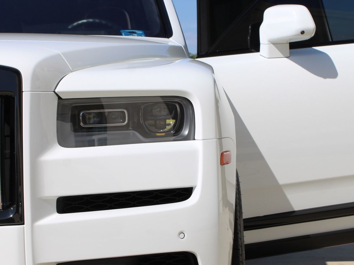 The front of a white Rolls-Royce Cullinan, door open during a mobile detail