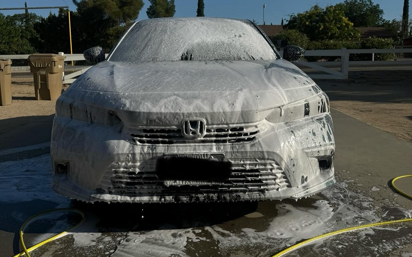 A foam covered sedan mid wash during a mobile detail
