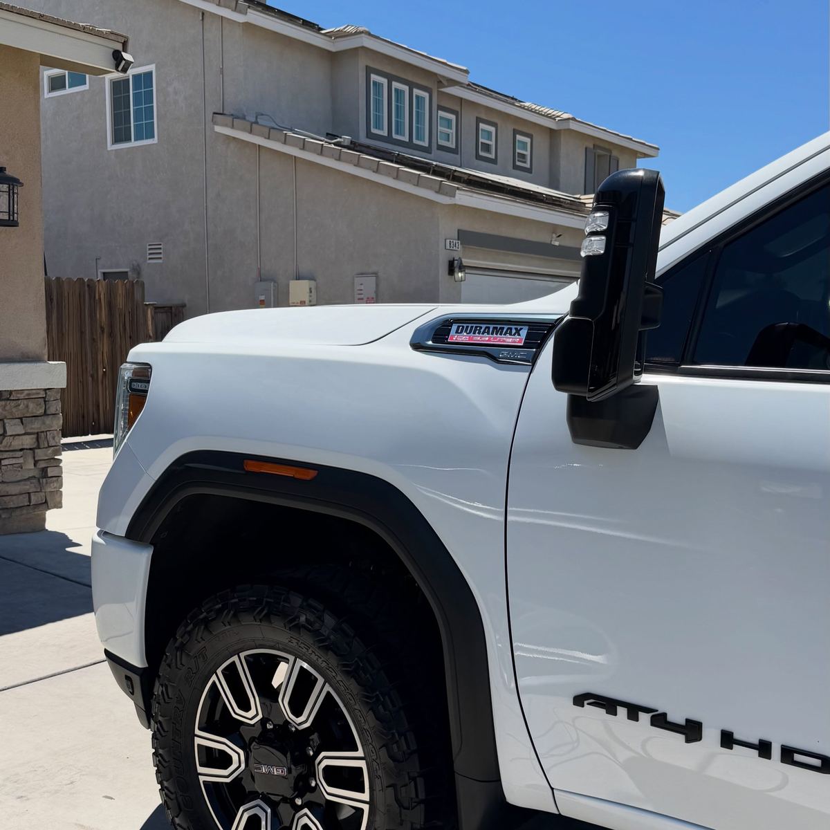 A white GMC Sierra AT4 HD in the sun, kept clean between visits