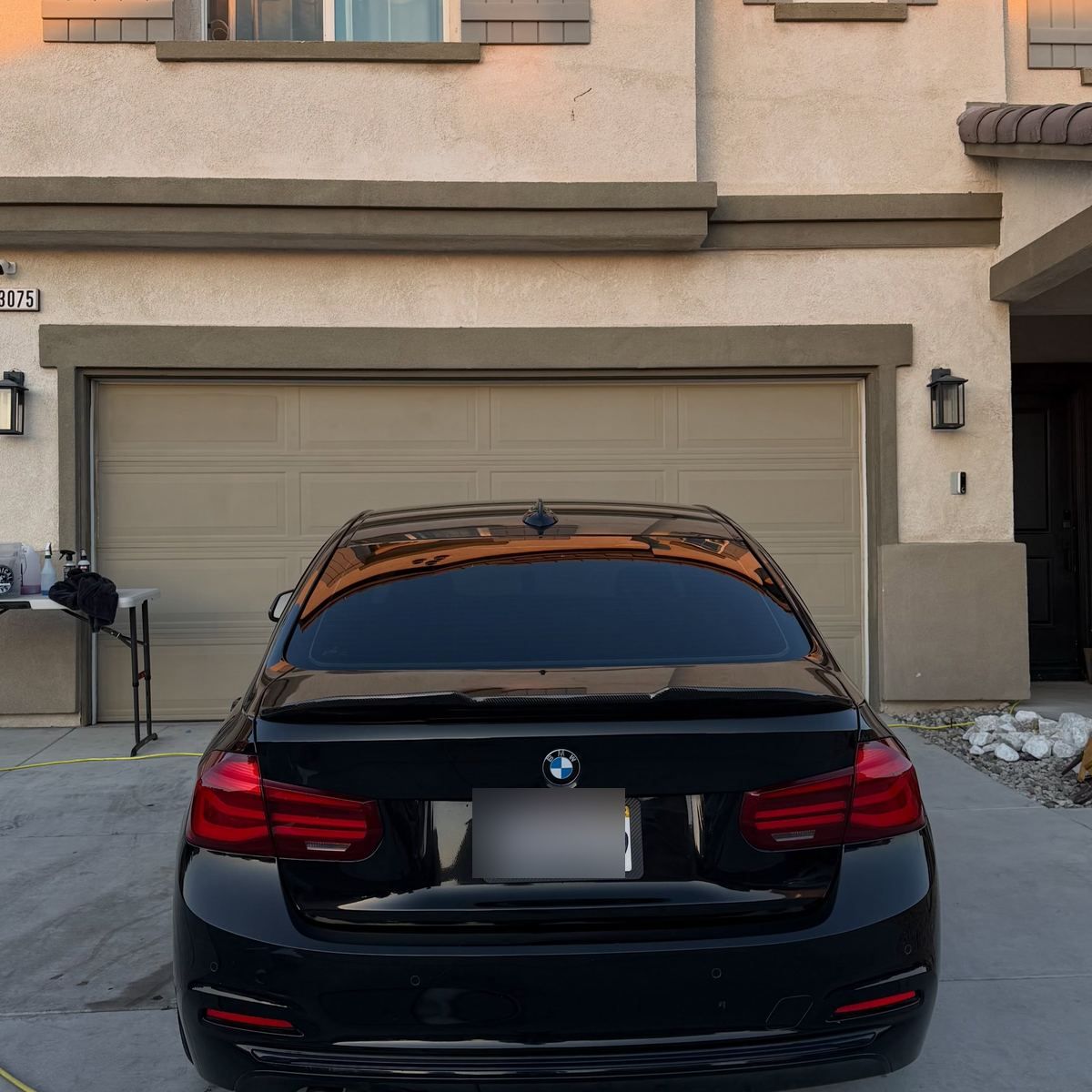 A black BMW 3 Series parked in a driveway after a wash