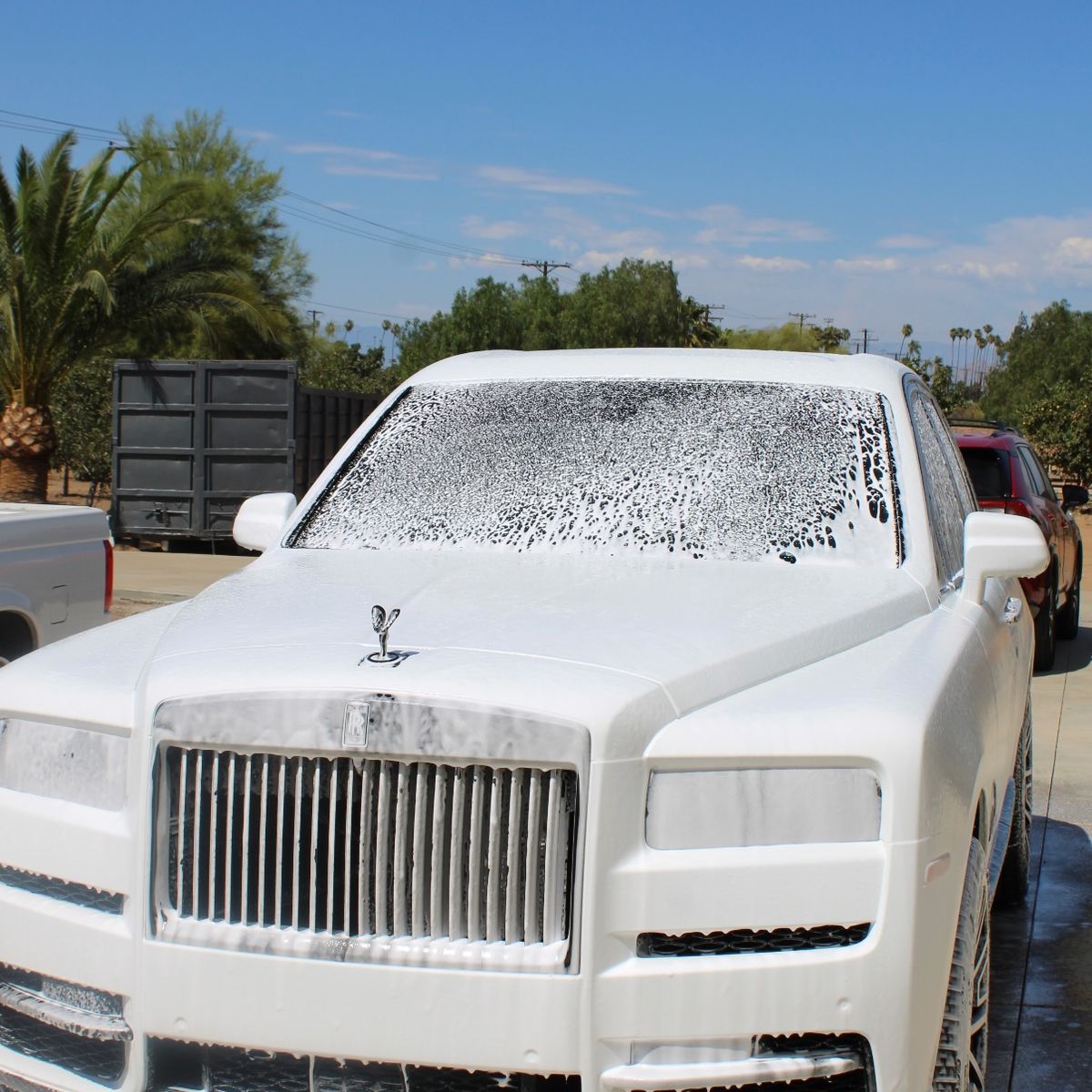 A white Rolls-Royce Cullinan covered in foam during a wash