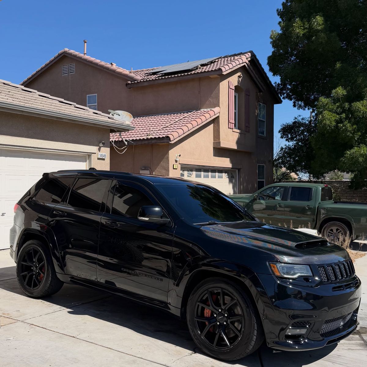 A black Jeep Grand Cherokee Trackhawk in profile in direct sun